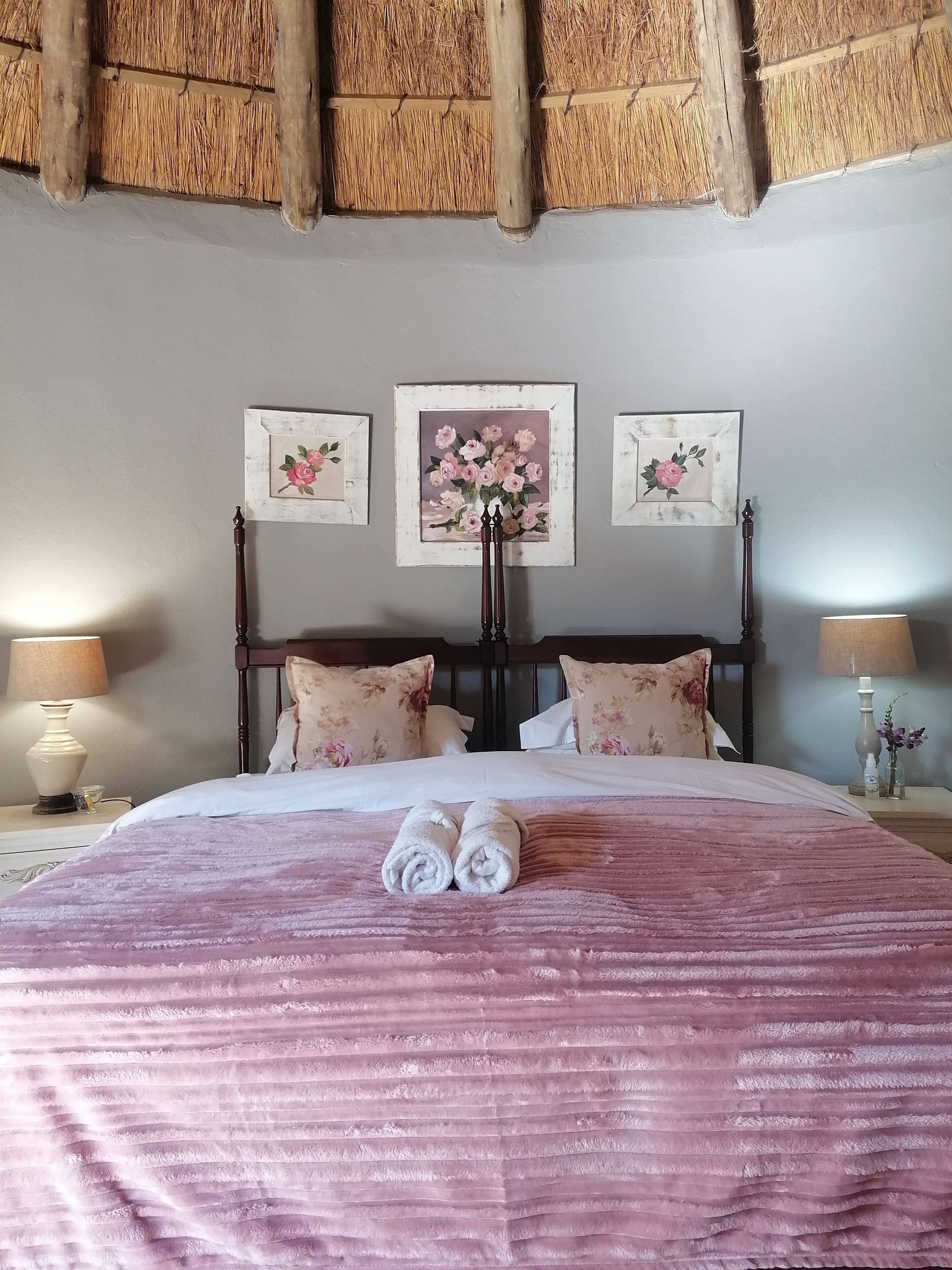 Une chambre avec un grand lit, une tête de lit en bois, des motifs floraux sur les murs et des lampes de chevet.