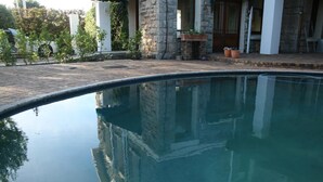 Una piscina amb parets de pedra i una zona pavimentada al fons.