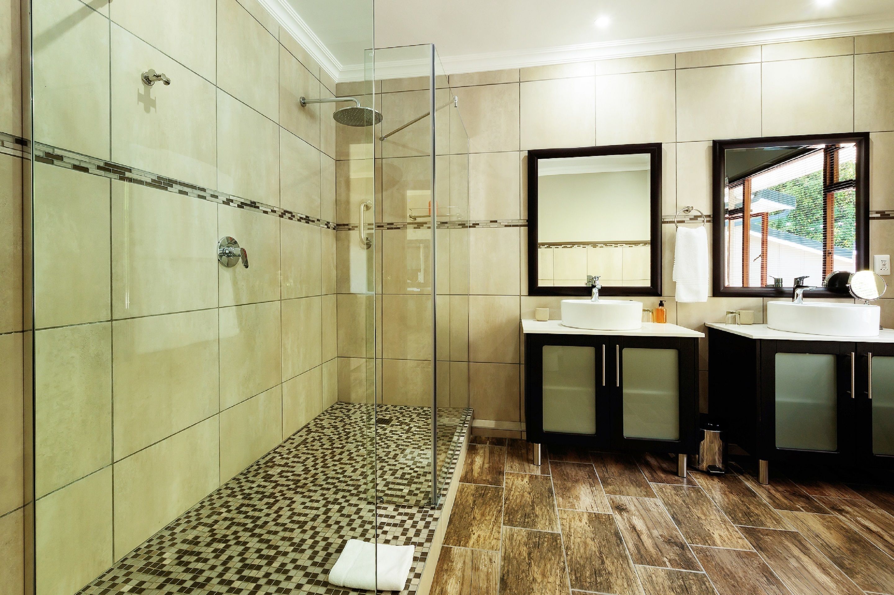A modern bathroom with a glass-enclosed shower, two sinks, and a large mirror.