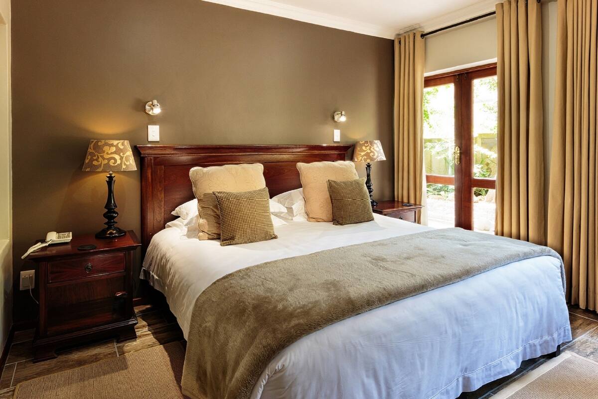 A neatly made bed with a wooden headboard, two bedside lamps, and a nightstand with a phone.