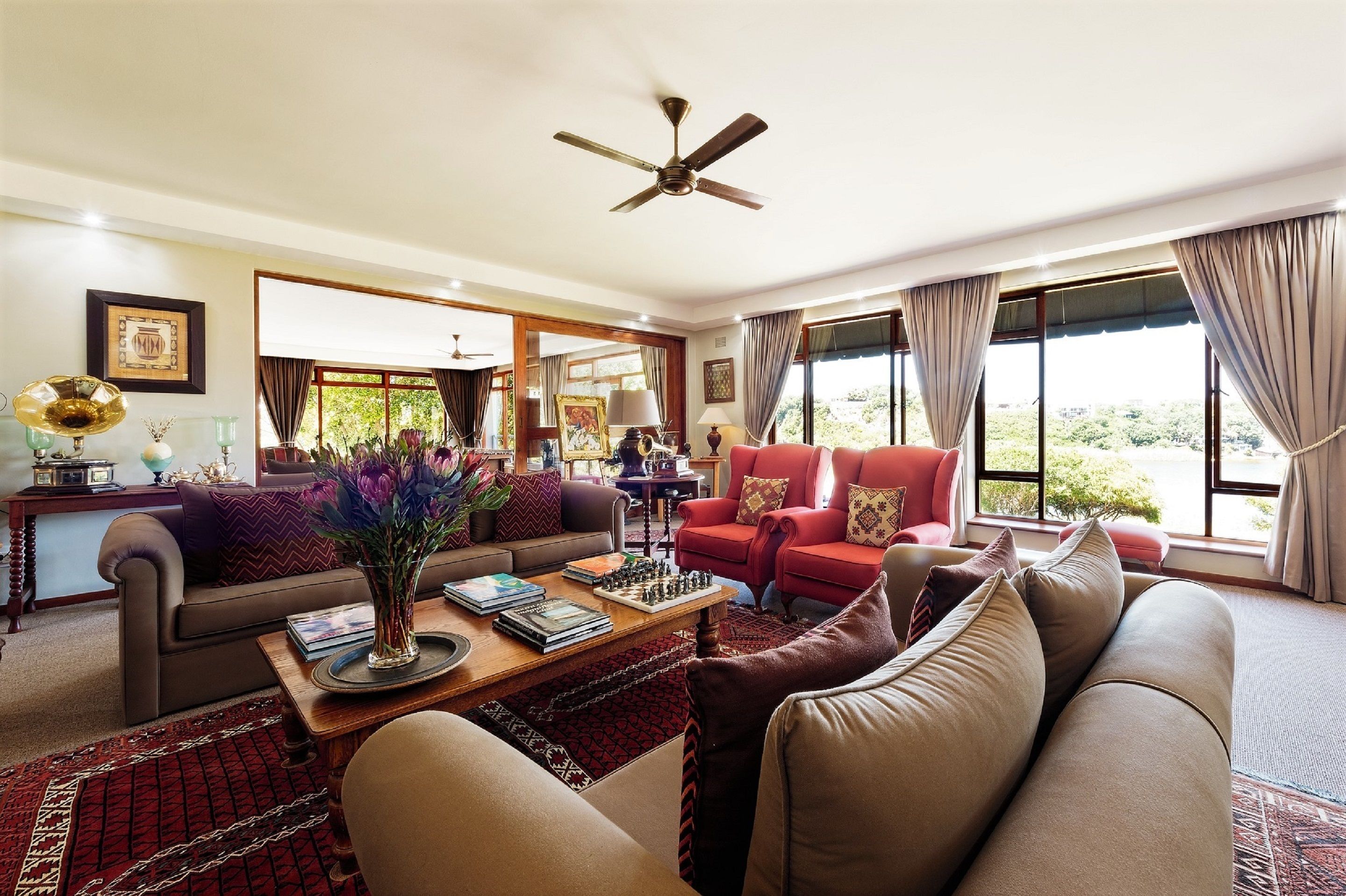 A well-lit living room with a sofa, armchairs, a coffee table, and a chessboard.