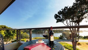 A balcony with a table, a bottle of wine, a glass, and a red menu. - Wilderness Manor (Wilderness)