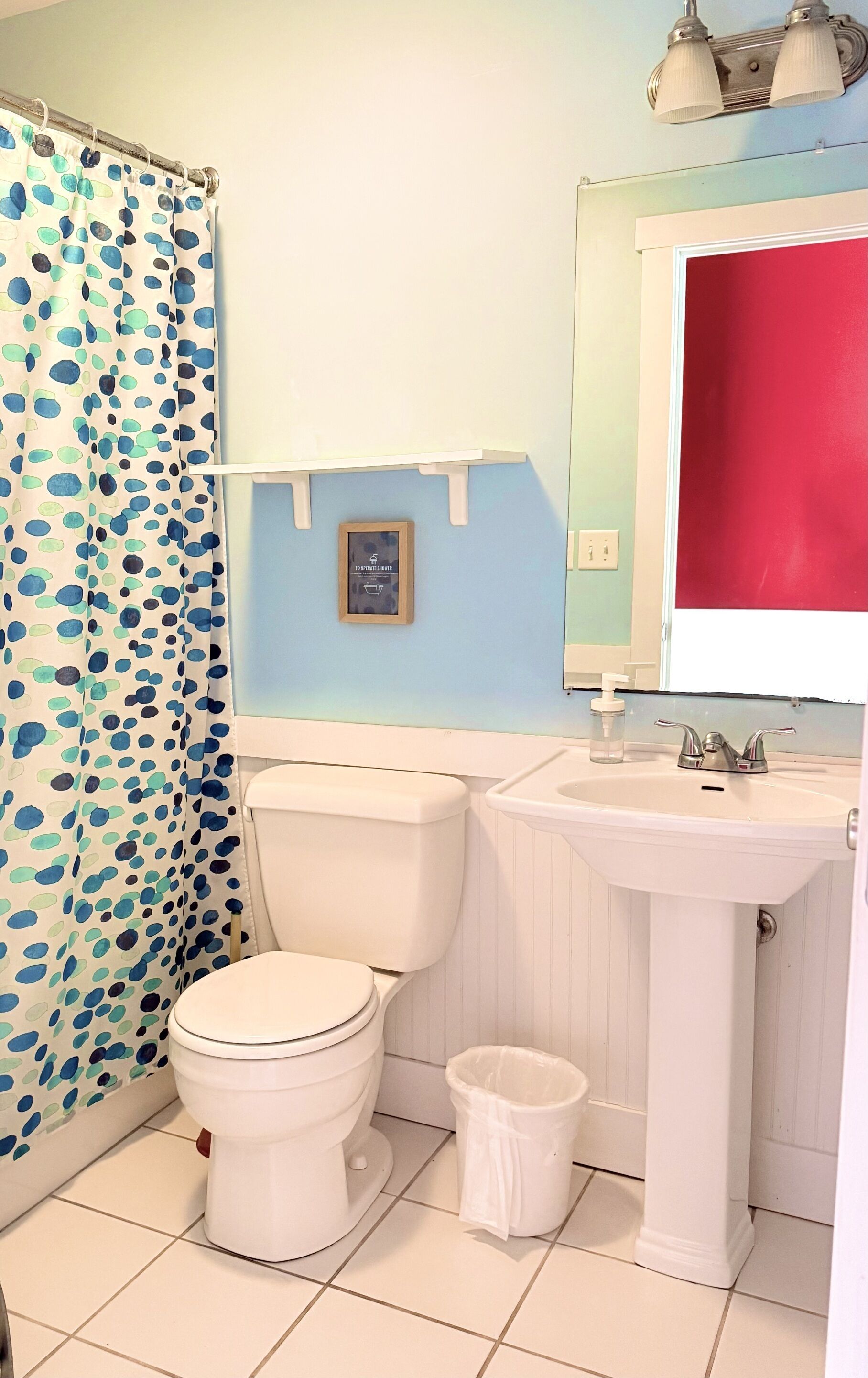 Un baño con inodoro, lavamanos y cortina de ducha.
