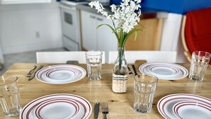 A dining table set with plates, cutlery, glasses, and a vase with flowers. - Blue Door Cottages (Monticello)