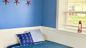 A bedroom with a bed, a window with blinds, and three red starfish decorations on the wall.