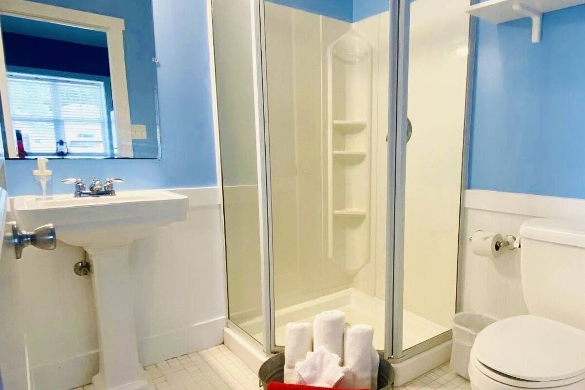Ein Badezimmer mit Duschkabine aus Glas, einem weißen Waschbecken und einer Toilette.