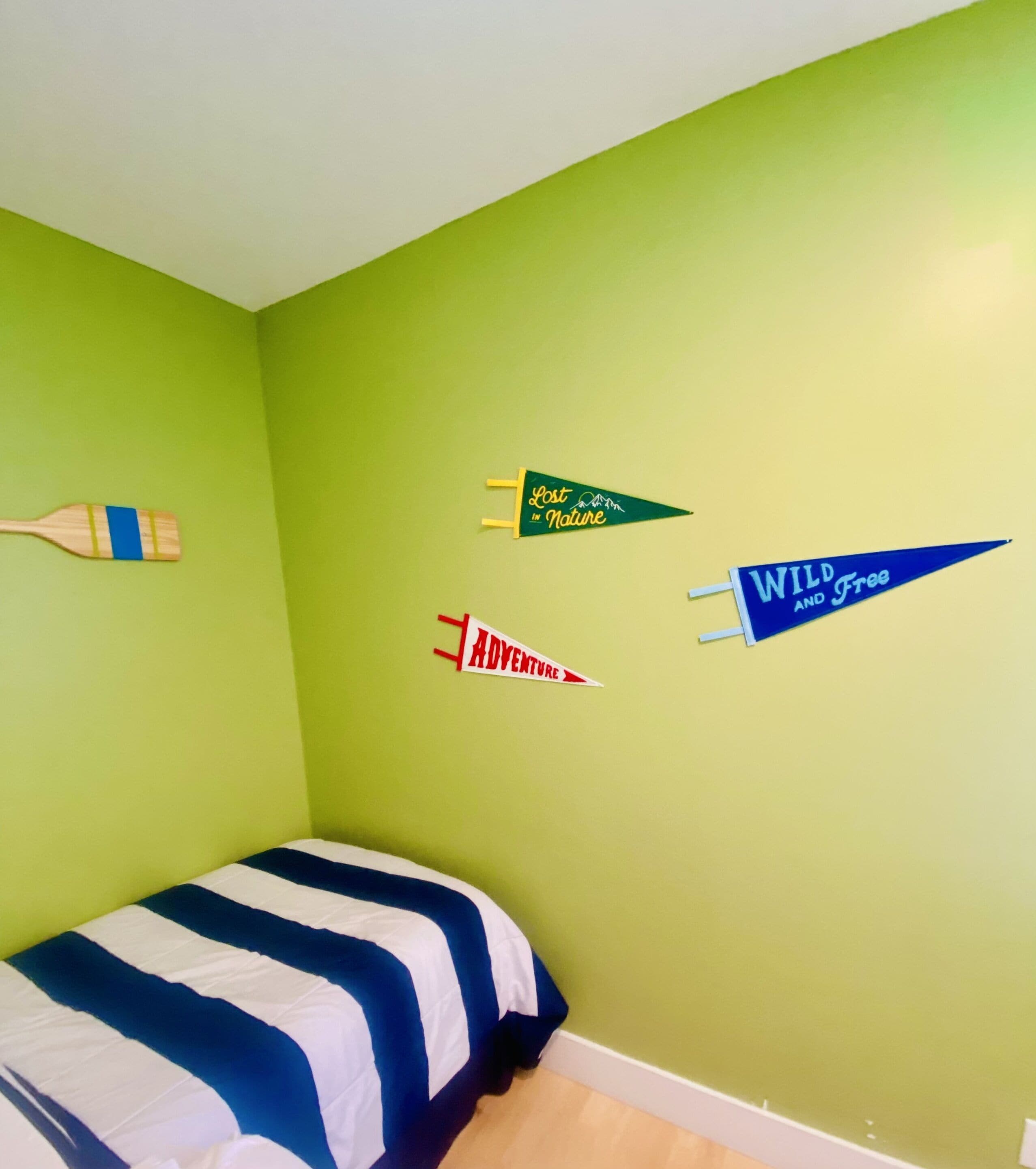 A bedroom with a bed, a green wall, and three pennant banners.