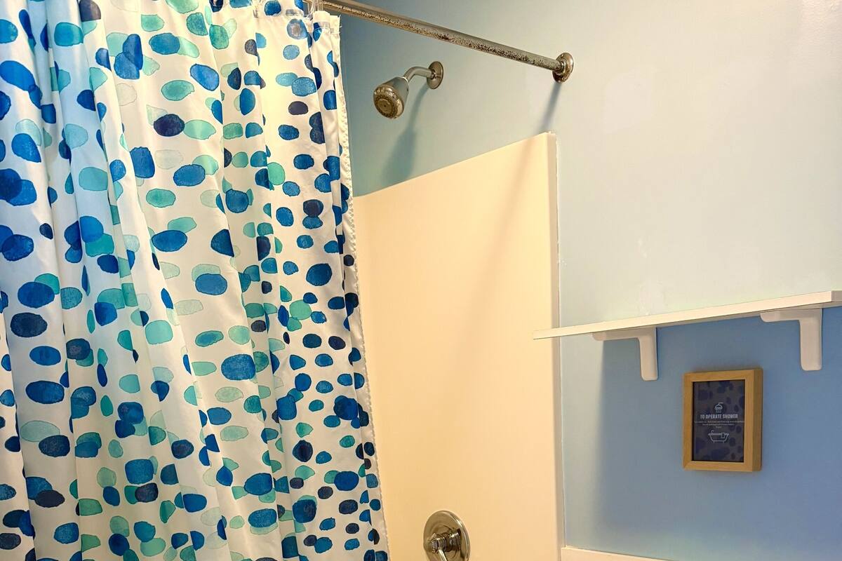 Ein Badezimmer mit Duschvorhang, Badewanne und Toilette.
