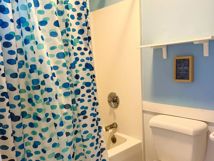 Une salle de bain avec un rideau de douche, une baignoire et des toilettes.