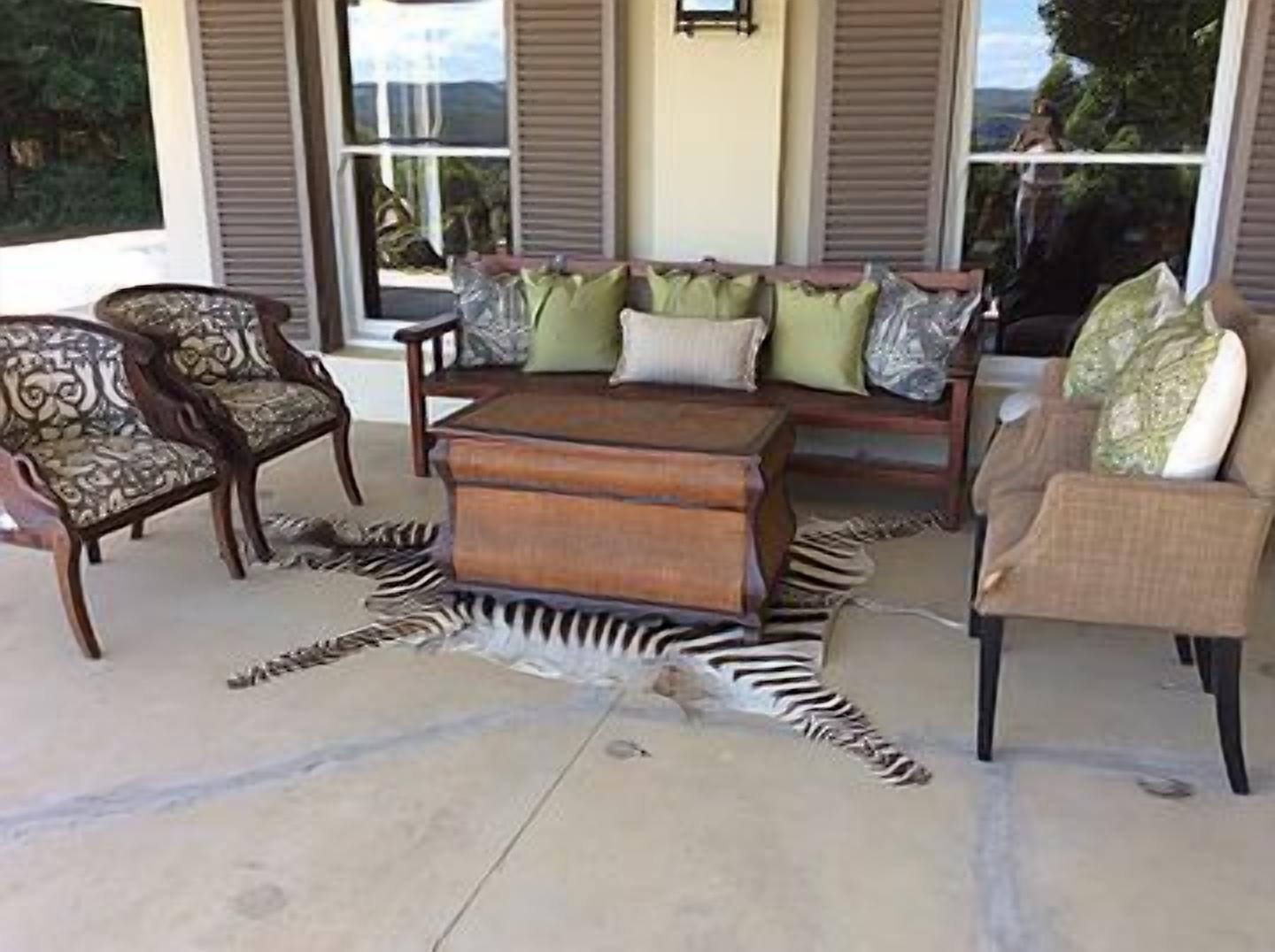 A living room with a sofa, two armchairs, a wooden coffee table, and a zebra rug.