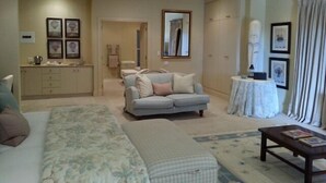 A living room with a sofa, a coffee table, and a dining area with a table and chairs. - Arum Hill Lodge (Balgowan)