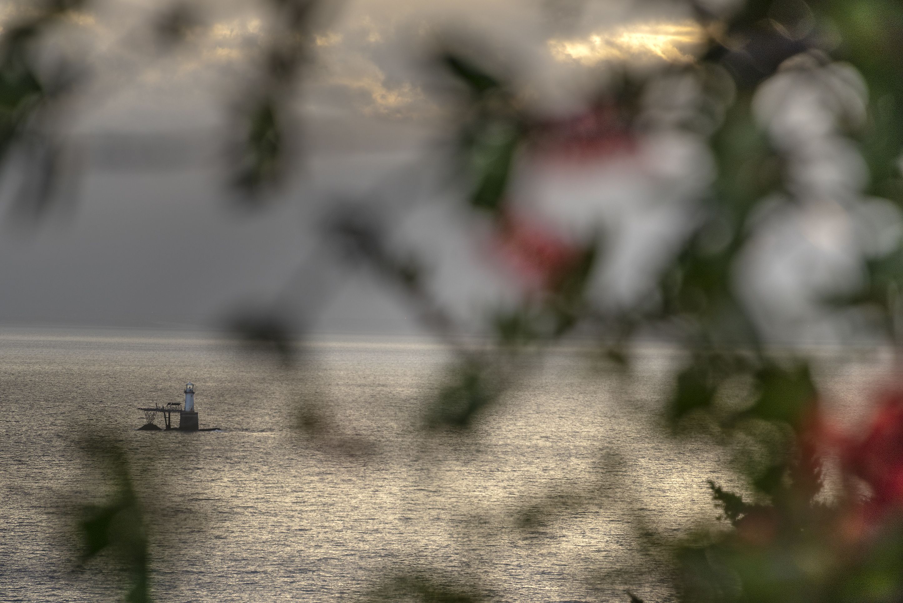 A lighthouse on a calm sea with a clear horizon.