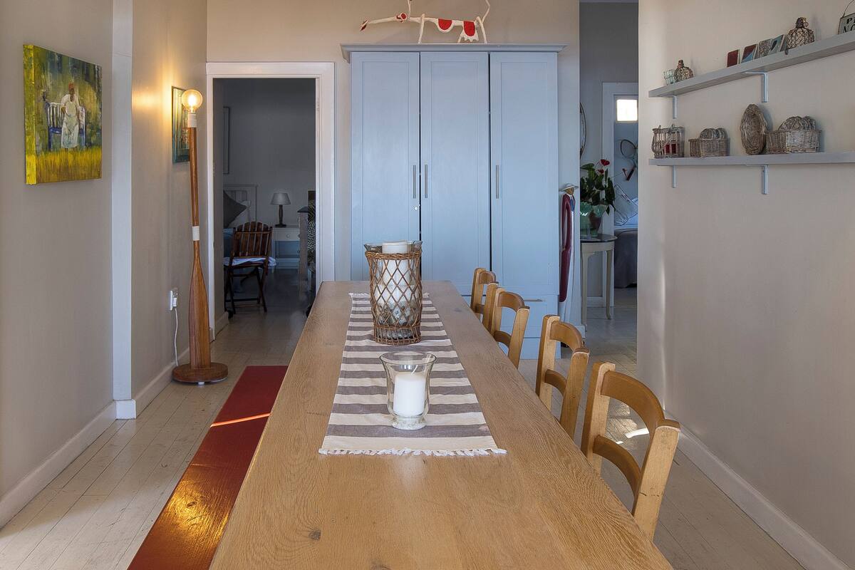 Ein Essbereich mit einem Holztisch, Stühlen, einer Kerzen-Dekoration und einem blauen Schrank im Hintergrund.