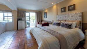 Ein Schlafzimmer mit einem großen Bett, einem Fernseher und einer Schiebetür zum Balkon.