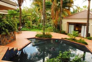A swimming pool surrounded by lush greenery and a tiled deck area.