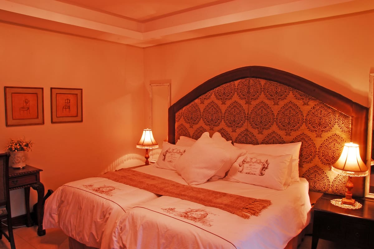 A bedroom with a large bed, two bedside tables, and two wall-mounted lamps.