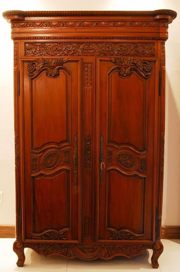 Un armario de madera alto y ornamentado con tallas intrincadas y un diseño clásico.