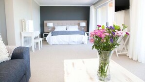 Une chambre d’hôtel avec un lit, des tables de chevet, une télévision et un vase de fleurs.
