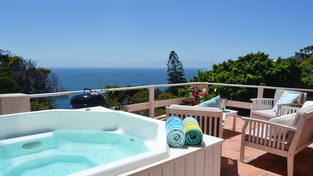 Un jacuzzi sur un balcon avec vue sur la mer, des meubles d’extérieur et une pergola.