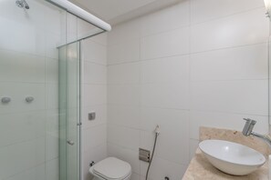 A bathroom with a glass shower enclosure, a white toilet, and a sink with a beige countertop. - Real Grandeza (Rio de Janeiro)