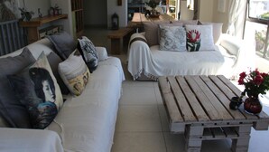 Ein Wohnzimmer mit einer Couch, einem Holztisch und einer Küche im Hintergrund.