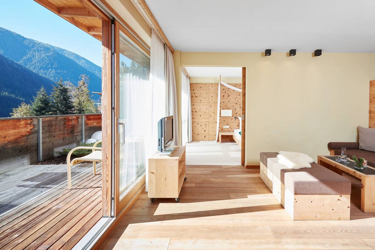 A modern, minimalist room with a wooden floor, a sofa, a TV, and a wooden headboard.