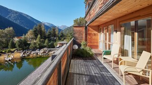 A wooden deck with a view of a lake and mountains. - AROSEA Life Balance Hotel (Ultimo)