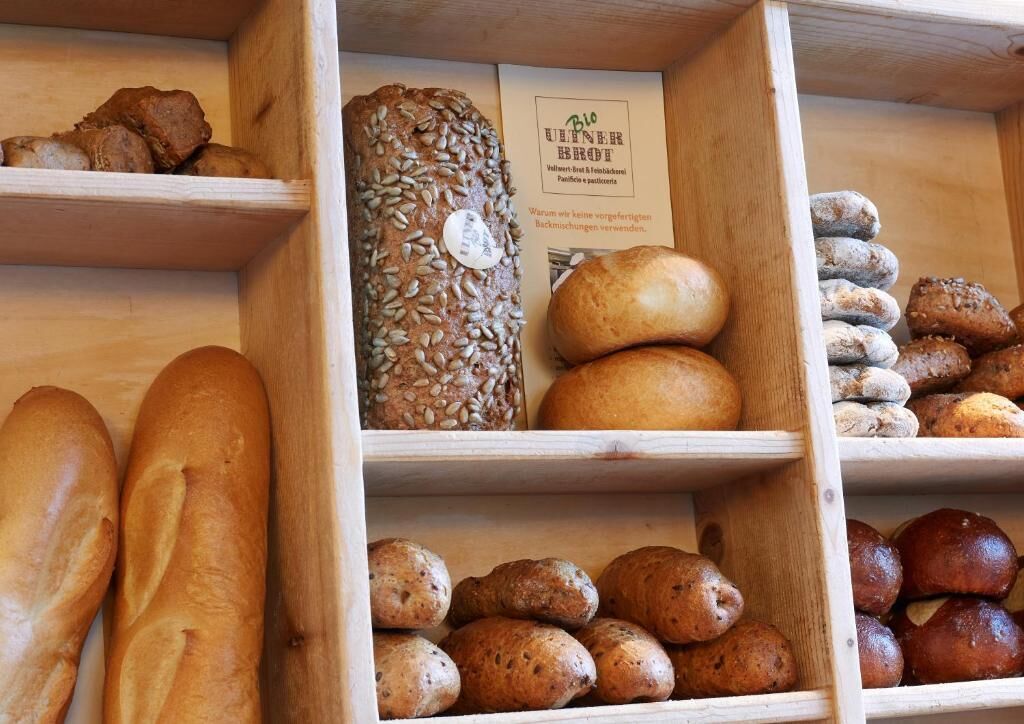 Des étagères en bois où sont exposés différents types de pain et de viennoiseries.