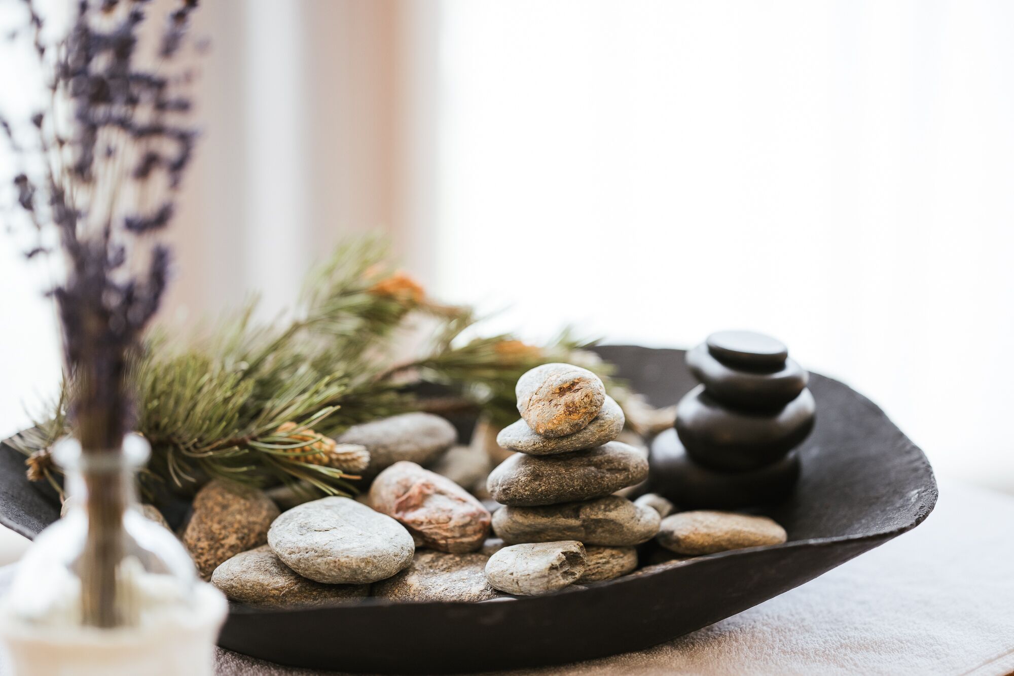 A black tray with a stack of smooth, rounded stones and a small, dark wooden object.