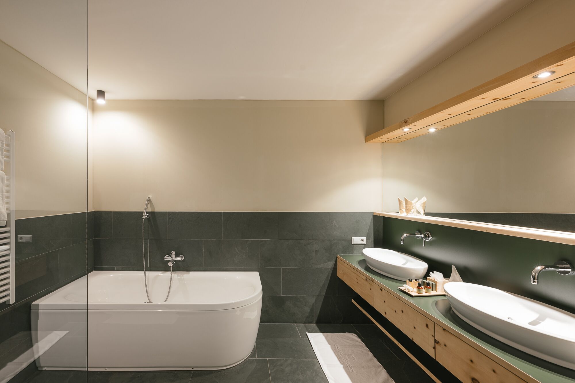 Un baño moderno con una bañera independiente, dos lavamanos y un espejo grande.