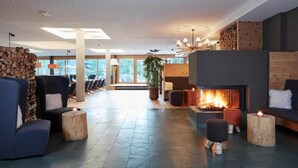 A modern lobby with a fireplace, seating area, and large windows. - AROSEA Life Balance Hotel (Ultimo)