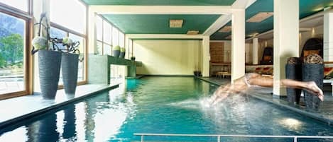 Una piscina techada, una piscina al aire libre, sombrillas