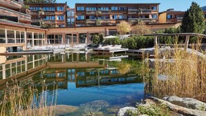 A modern hotel with a courtyard featuring a reflective pond, outdoor seating, and a view of the surrounding buildings. - AROSEA Life Balance Hotel (Ultimo)