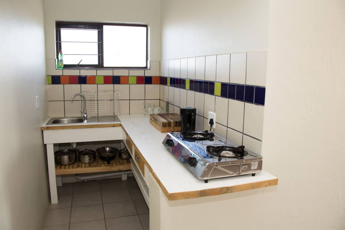 A compact kitchen with a gas stove, sink, and a window above the countertop.