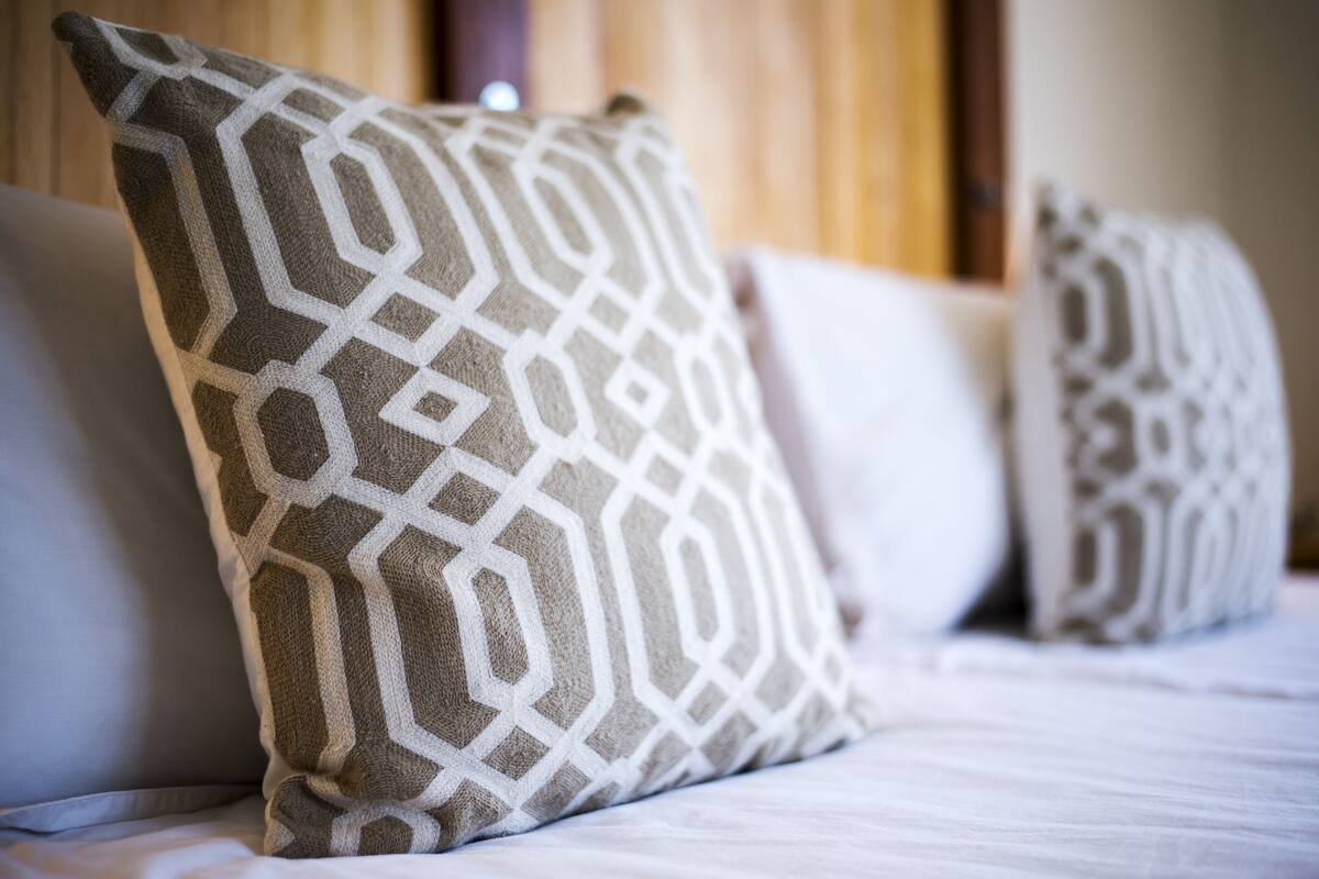 A bed with multiple pillows, one with a geometric pattern.