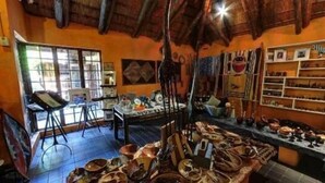 A rustic interior with wooden beams, a pottery display, and a painting easel. - Blue Cottages (Hoedspruit)