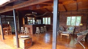 A spacious wooden cabin interior with a bar area, wooden furniture, and large windows.