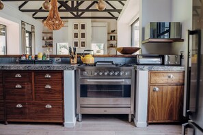 Una cocina moderna con horno empotrado, estufa a gas, armarios de madera y una lámpara colgante.