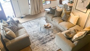 A modern living room with a grey sofa set, a coffee table, and a patterned rug. - Rockwood Lodges (Karkloof Nature Reserve)