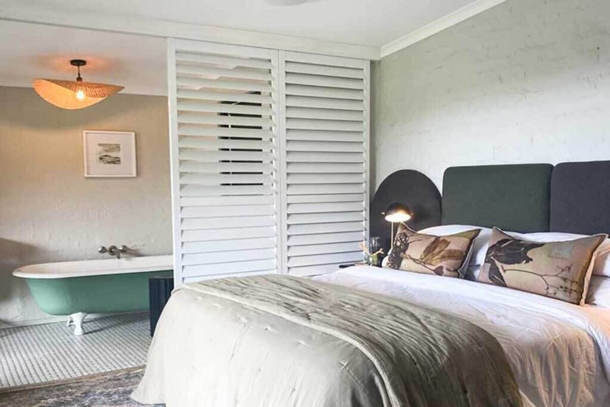 A bedroom with a bed, a vanity, a hanging light fixture, and a ceiling fan.