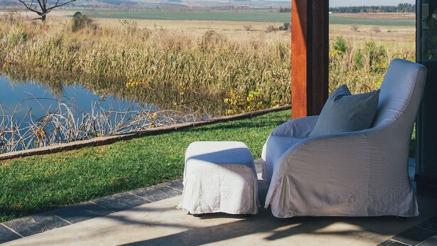 A modern outdoor seating area with a view of a field and distant hills. - Rockwood Lodges (Karkloof Nature Reserve)