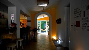 En hall med ett klinkergolv, en bardisk med barstolar och en trappa som leder till ett annat rum.