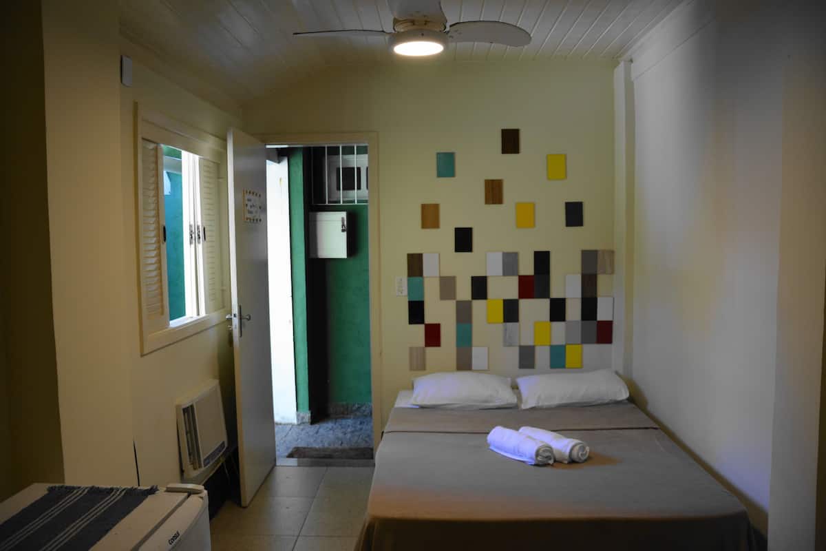 A hotel room with two beds, a small kitchenette, and a wall with a colorful abstract art piece.