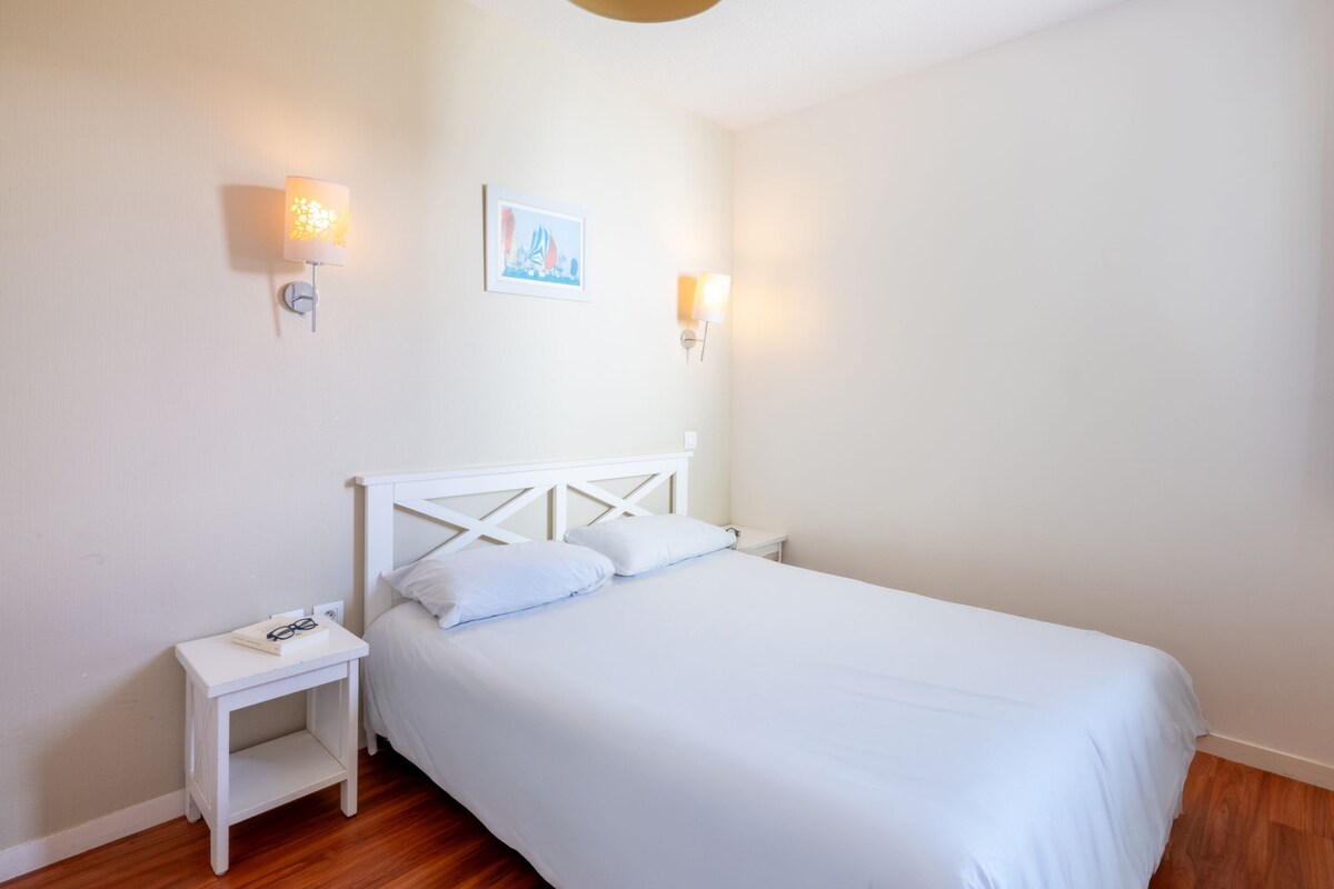 Una camera da letto con un letto bianco, due comodini e luci a parete.