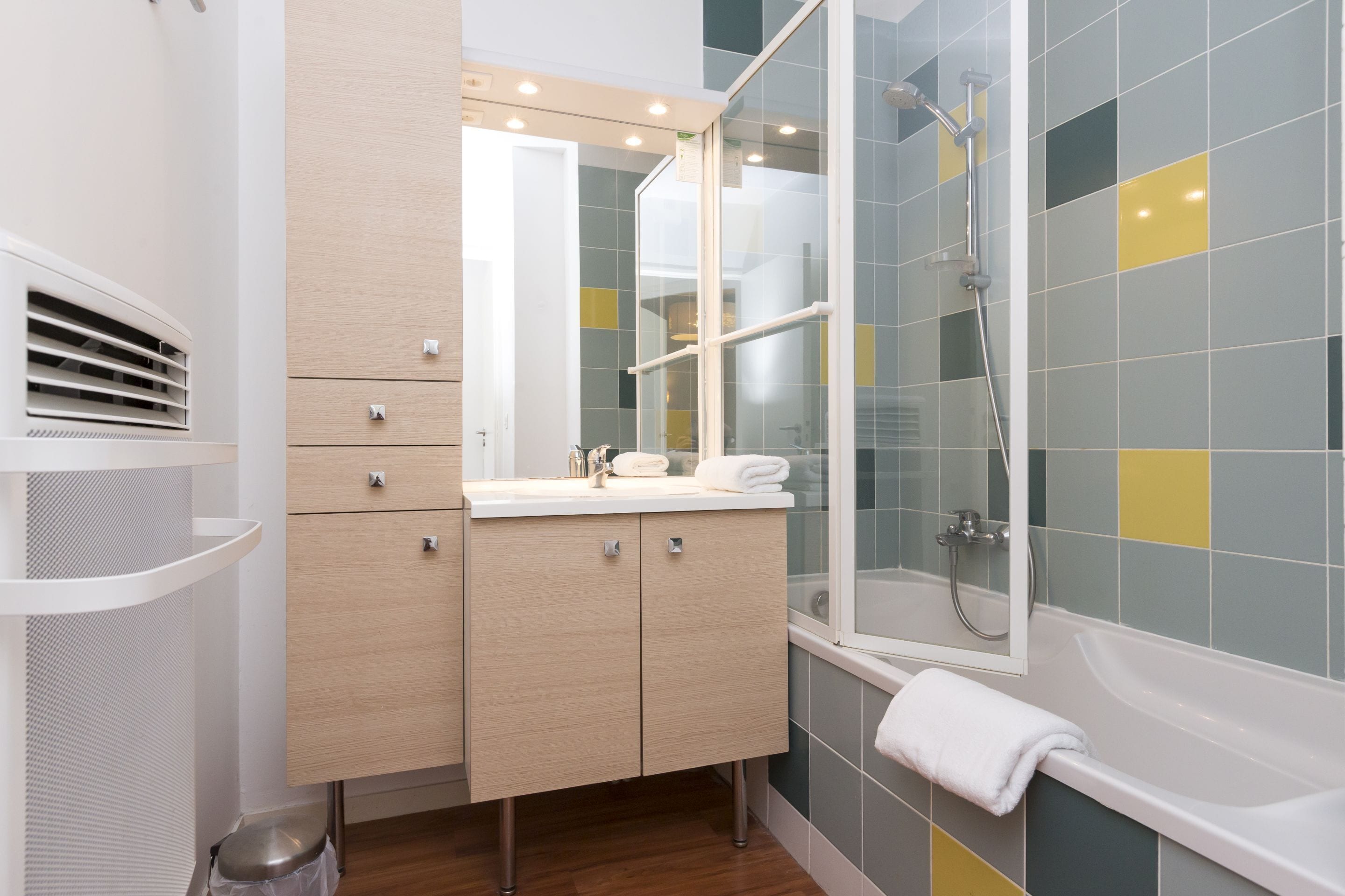 Un baño moderno con ducha de vidrio, tocador con espejo y bañera.