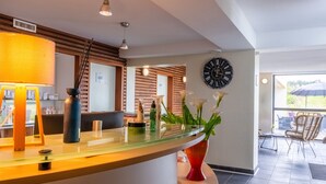 A reception area with a curved counter, a clock, and a vase with flowers. - Résidence Odalys Fleur de Sel (Guidel)