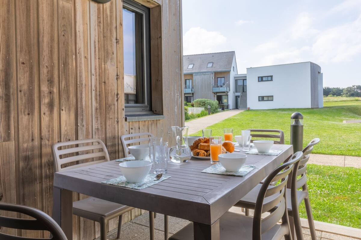 A wooden table set for breakfast with a view of modern buildings in the background.