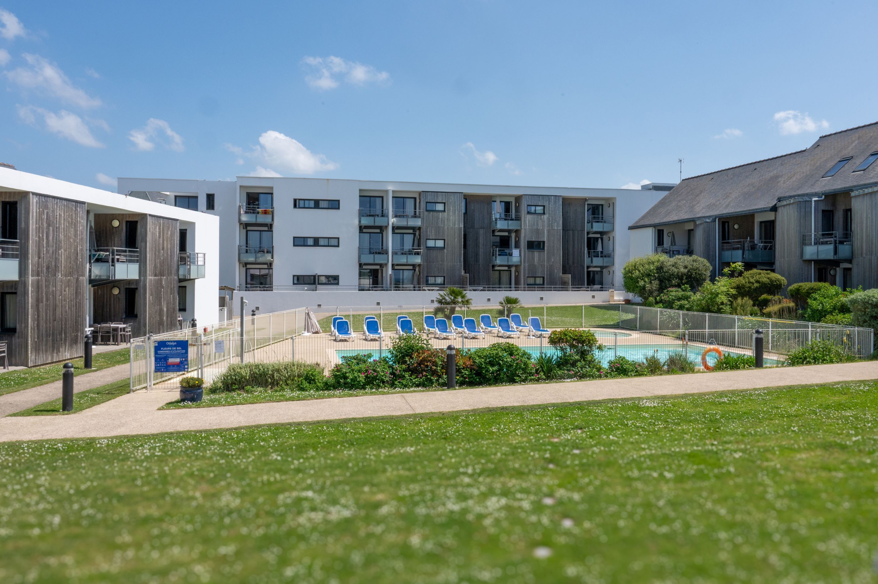 Un bâtiment moderne doté d’une piscine, d’un espace extérieur aménagé et d’une pelouse bien entretenue.