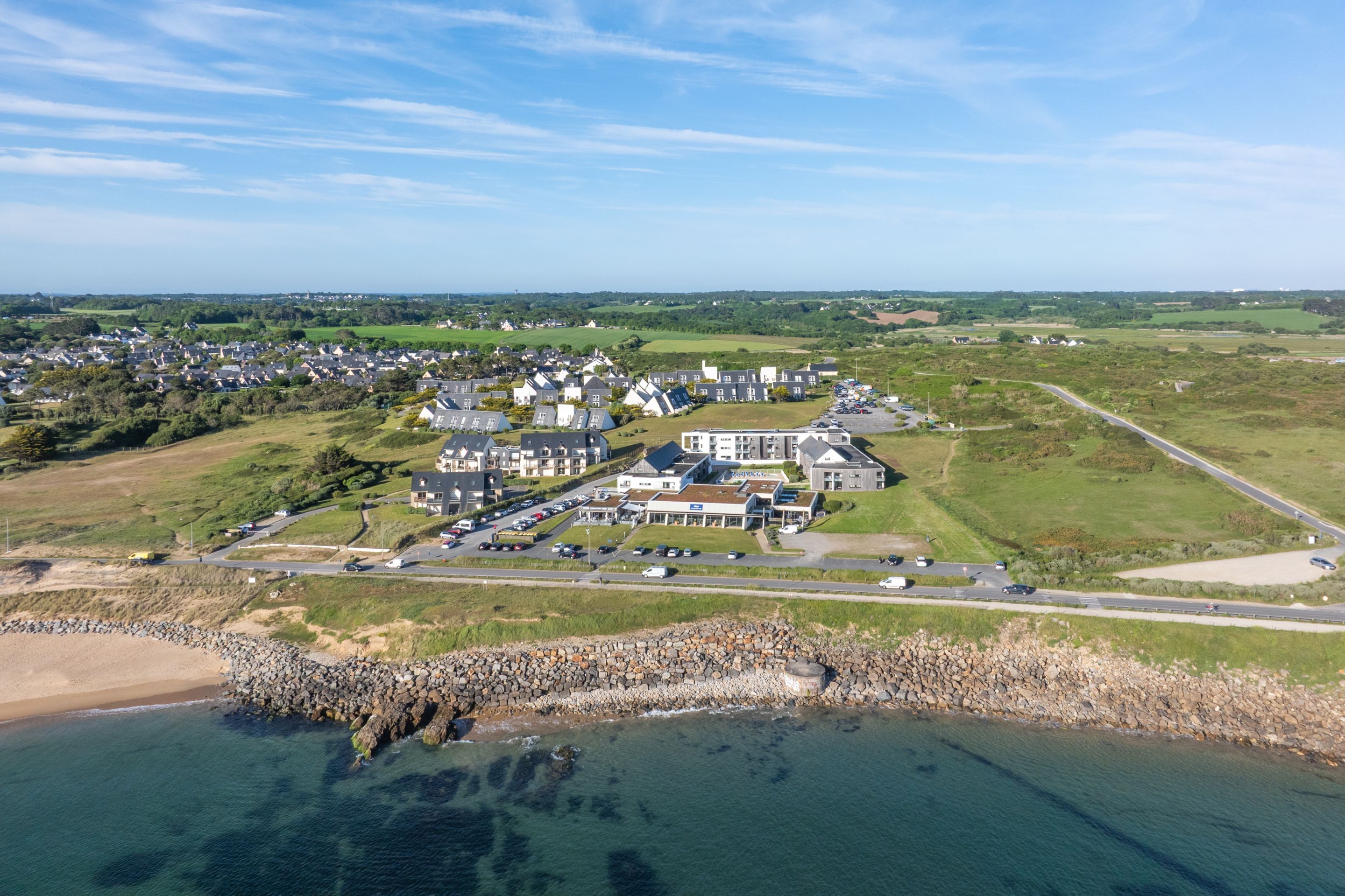 Vue aérienne d’une ville côtière avec des immeubles résidentiels, un port de plaisance et une côte rocheuse.