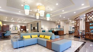 Un vestíbulo espacioso con un sofá modular grande, un mostrador de recepción e iluminación moderna.